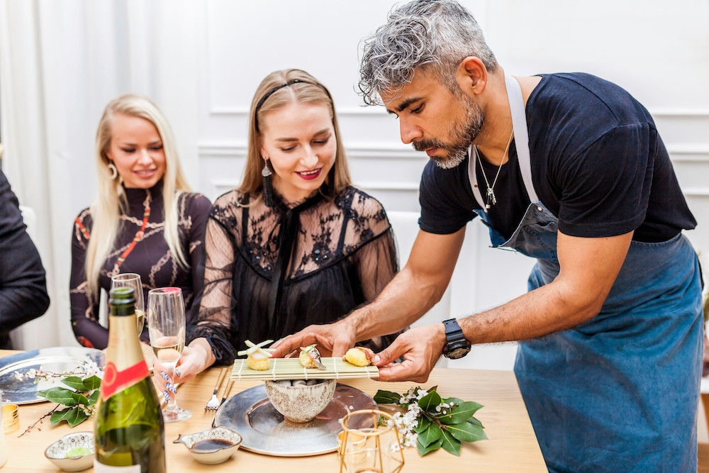 A private chef serving food to clients at a table during a private dinner at home. 