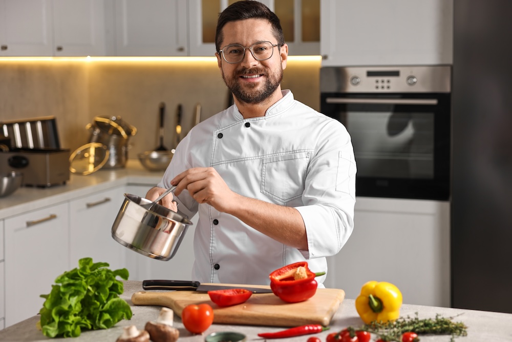 A professional chef is cooking a meal at the table in the kitchen.
